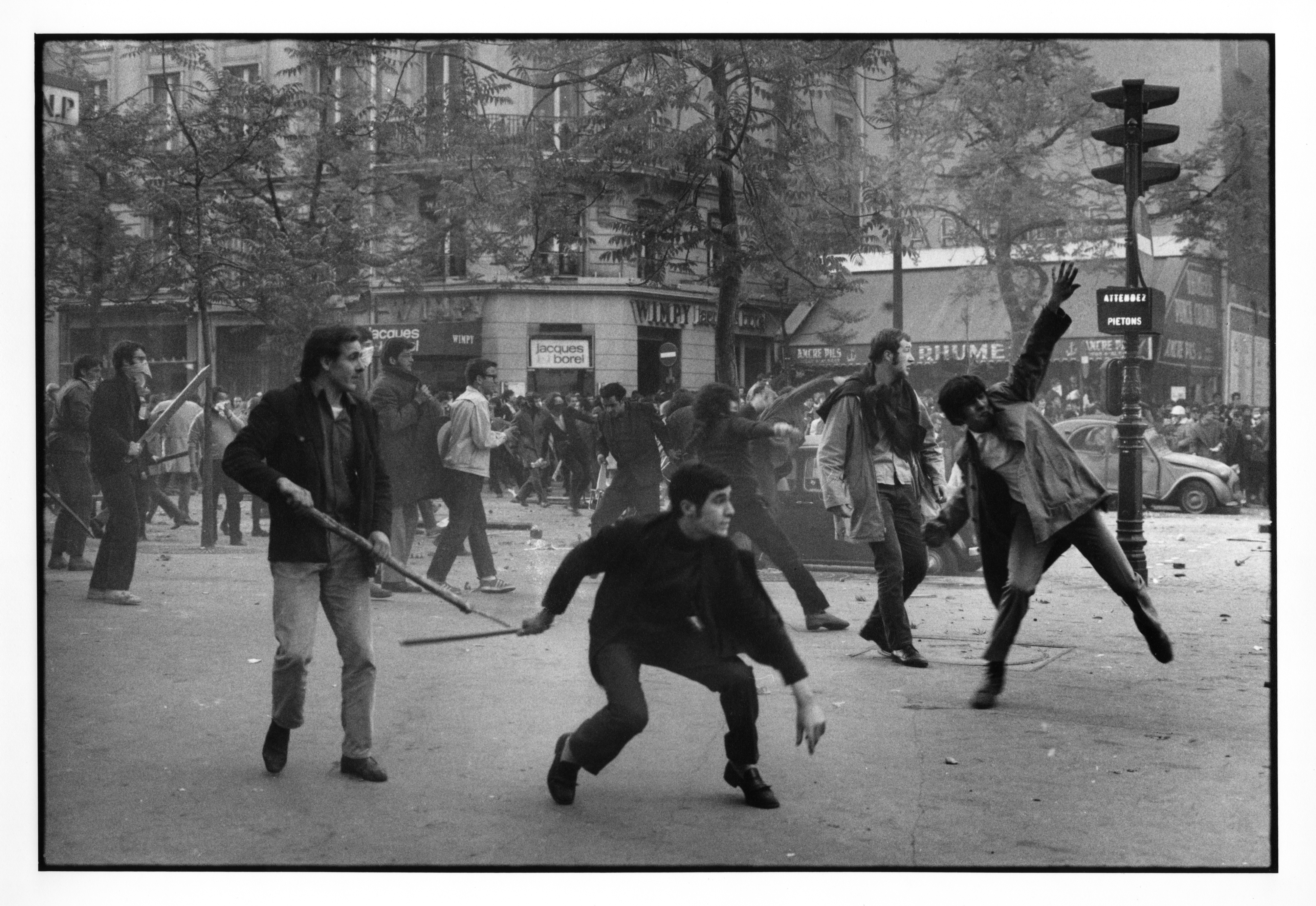BRUNO BARBEY -  May 1968, Paris. 6th arrondissement. Boulevard Saint Germain. Students hurling projectiles against the police. Vintage silver gelatine print © BRUNO BARBEY